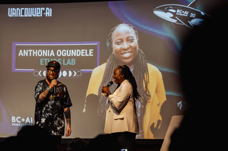 Anthonia Ogundele steps to the mic beside the host as her name and Ethos Lab branding light up the slide behind them.