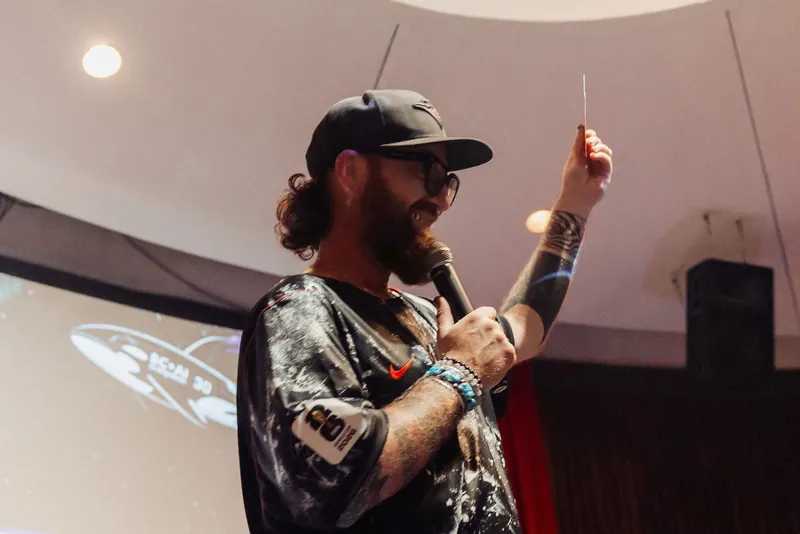A candid side profile of the MC holding the microphone as the dome ceiling arches softly overhead.