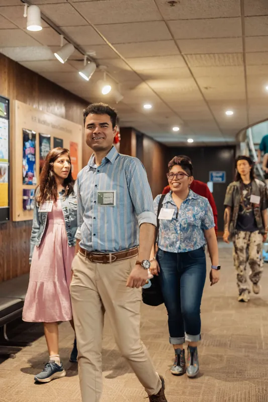 Badge-wearing attendees stride together through a corridor inside the H.R. MacMillan Space Centre.