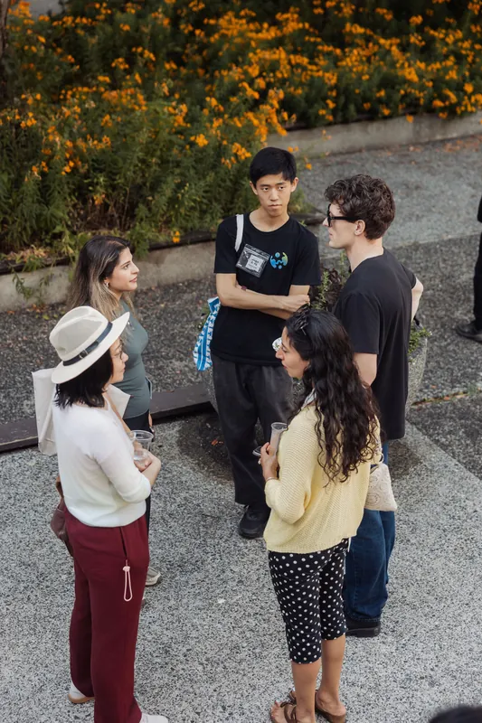A small group of attendees deep in conversation on the plaza beside the Space Centre's marigold beds.