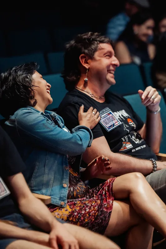 Two audience members share a spontaneous laugh together in the theater seats during the evening program.