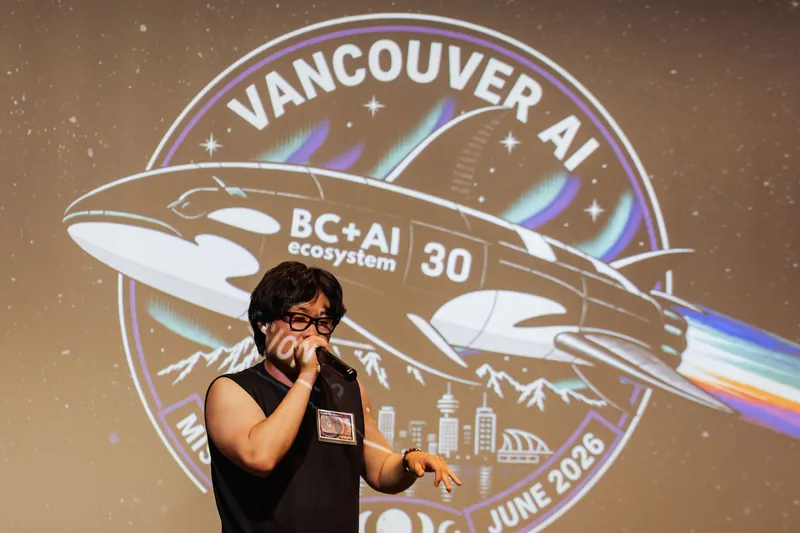 The performer extends an arm mid-set at the Space Centre, the Vancouver AI event slide lit behind them.