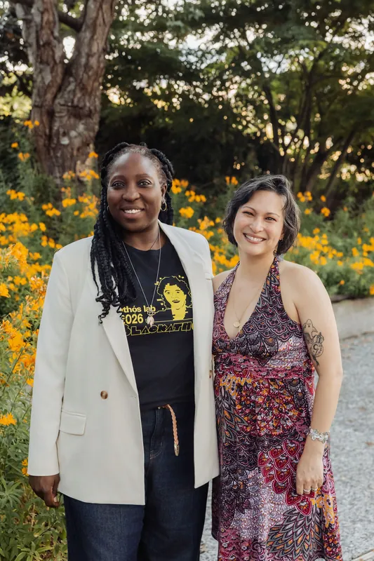 Two attendees smile together for a photo in the blooming Space Centre garden at golden hour.
