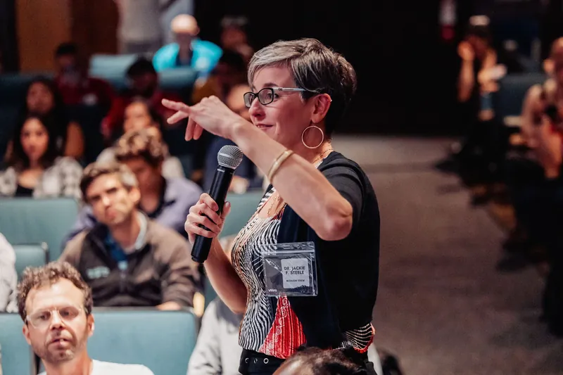 The roving mic runner approaches as the attendee with the microphone holds the room's full attention.