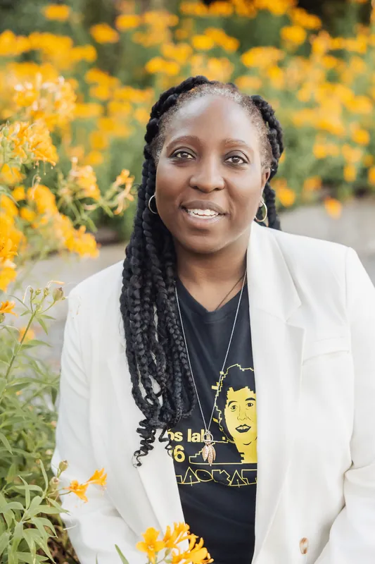 Yellow flowers frame a close-up portrait of a woman in a white blazer glowing in the evening light.