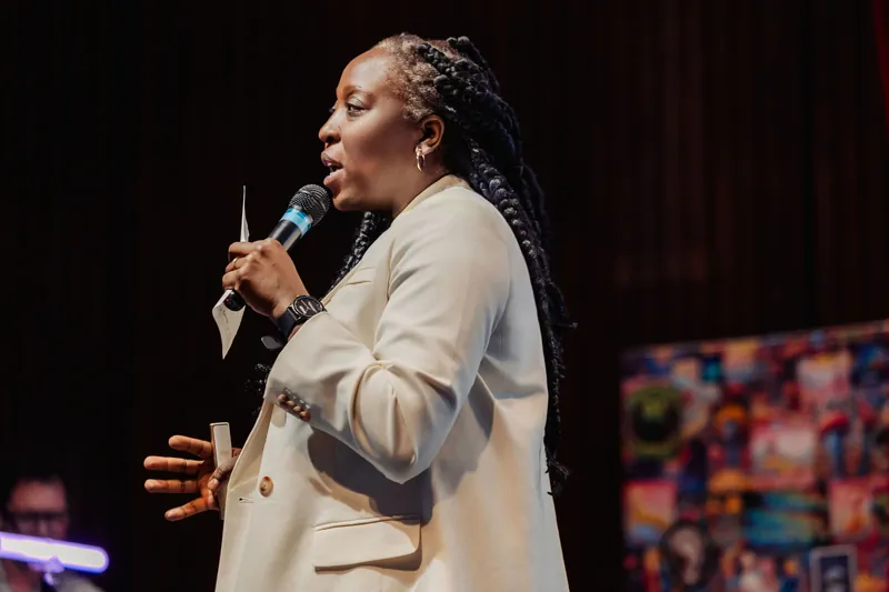 A profile shot catches Anthonia Ogundele in full oratorical stride, a vivid mural lending color to the stage backdrop.