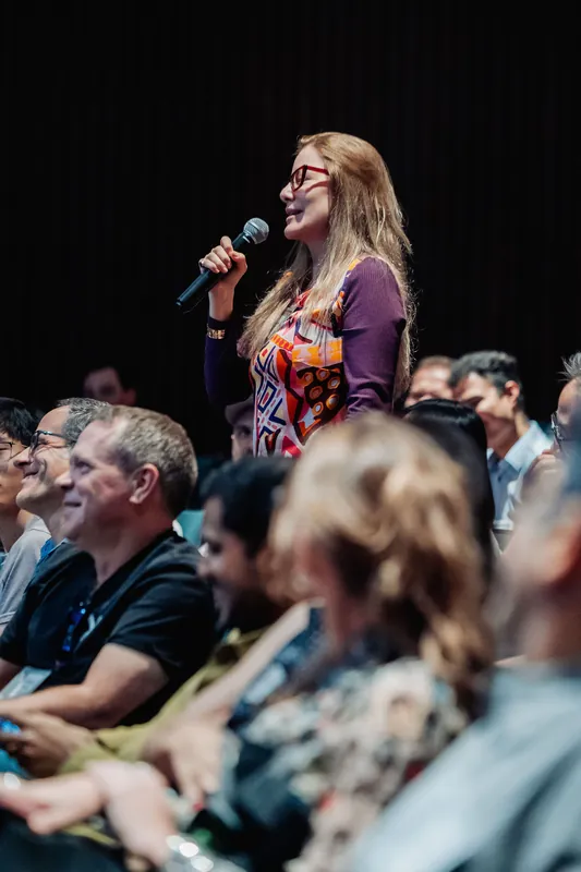 The same audience member continues her question as laughter and engagement ripple through the seats around her.