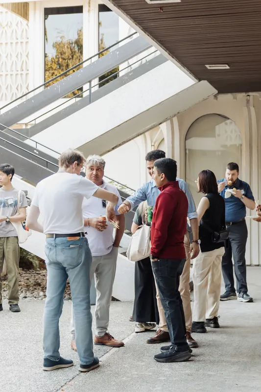 Attendees shake hands and mingle in warm golden light on the outdoor plaza of the Space Centre.