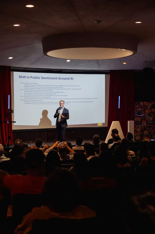 The audience watches from their seats as a speaker presents on shifting public sentiment around AI.