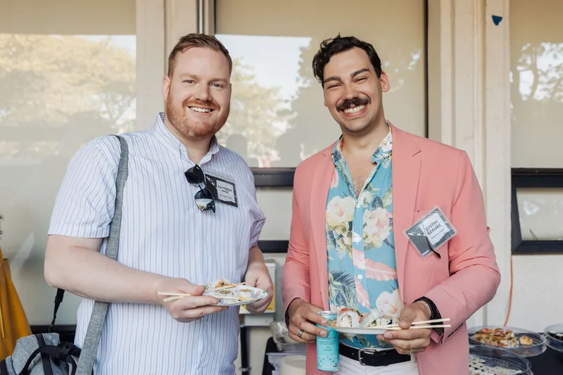 Two attendees enjoy plates of sushi and easy laughter during the Space Centre catered reception.