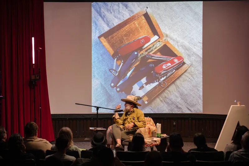 Dave Olson's talk opens with archival images and story slides behind him — Stage-left view.