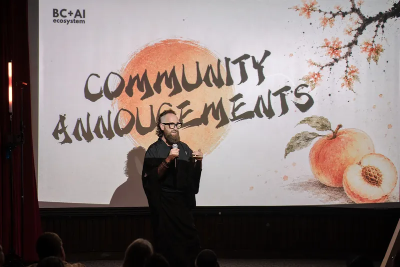 Community Announcements open with Kris on stage beside the peach-framed slide — Stage-right view.