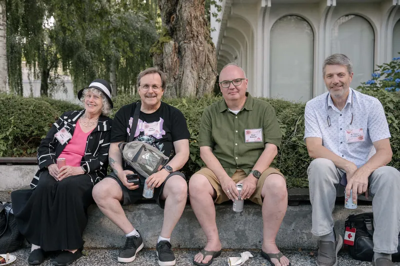 Guests smile for the camera with plates of BBQ on the outdoor patio.