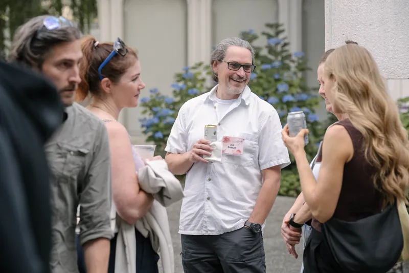 Crowds fill the courtyard for outdoor networking in the late-day light — Soft focus on the crowd edge.