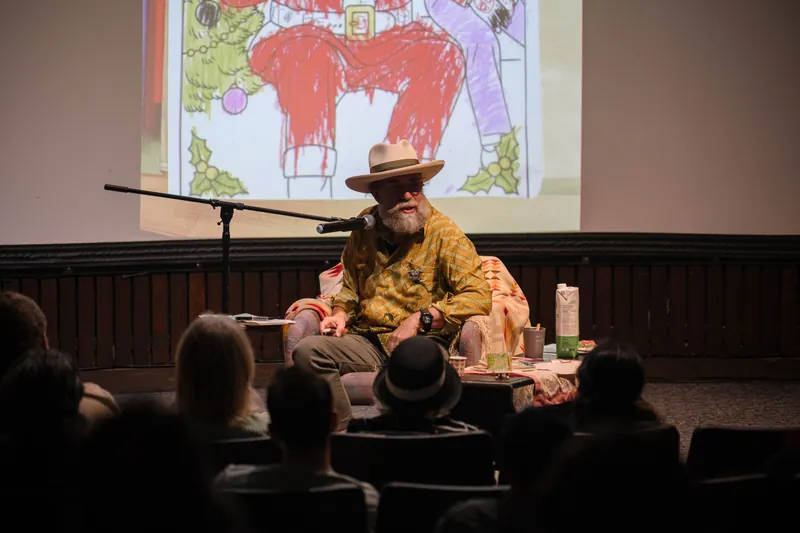 Dave Olson continues from the armchair as denser text and photo slides roll — Tight frame.