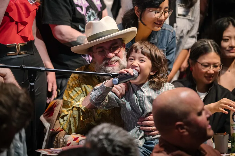 Dave Olson shares the mic with a young guest on stage.