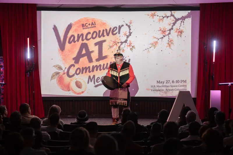 An Indigenous welcome unfolds on stage as the audience settles in — Soft focus on the crowd edge.