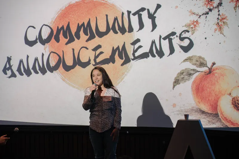 A community announcer shares updates from center stage — Stage-left view.