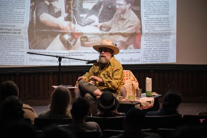 Dave Olson leans into storytelling — clippings, collages, and handwritten notes on screen — Screen bright in the background.