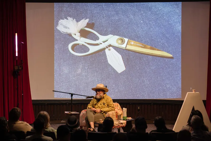 Dave Olson's talk opens with archival images and story slides behind him — Soft focus on the crowd edge.