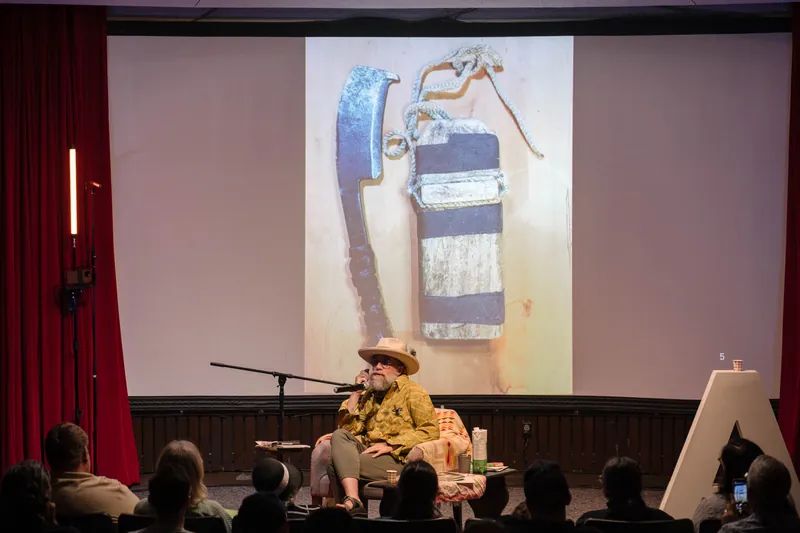 Dave Olson's talk opens with archival images and story slides behind him — Stage-right view.