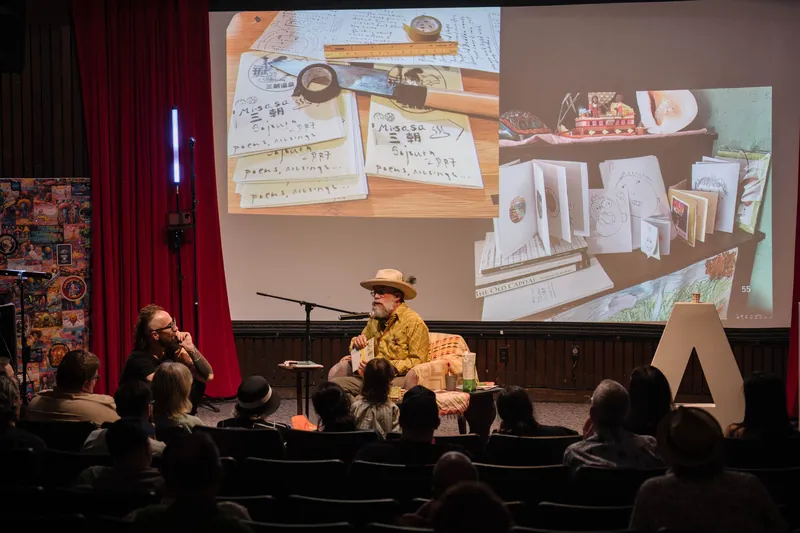 An on-stage conversation with Dave Olson — two chairs, mic, and a listening room — Audience heads in the foreground.