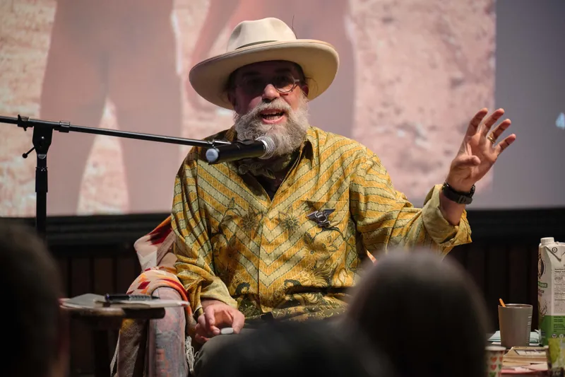 Dave Olson continues from the armchair as denser text and photo slides roll — From the aisle.