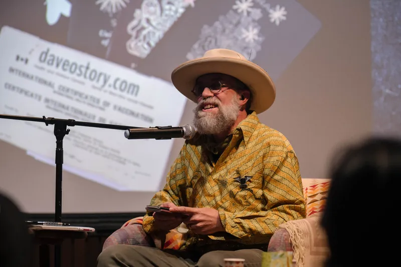 Dave Olson continues from the armchair as denser text and photo slides roll — From the aisle.