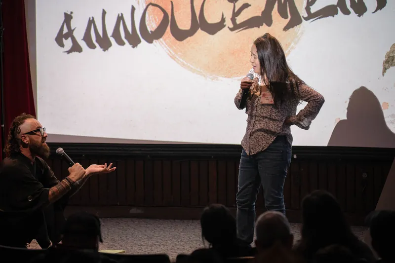 More community announcements roll on — mic handoffs and short stage spots.