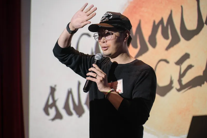 A community announcer in hat and shades takes a quick mic turn.