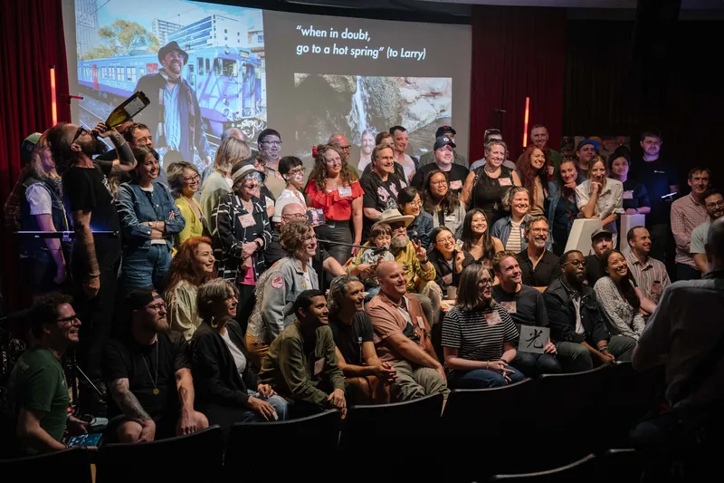 Wide group photo attempt — the room piles onto the stage apron.