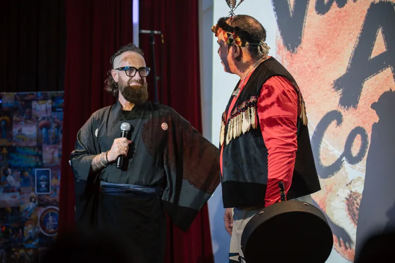 Welcome speakers share the stage — drum and mic catching the spotlight.