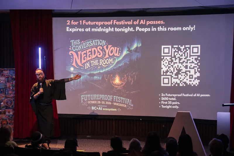 Kris points to Futureproof Festival calls-to-action and QR codes on screen — Stage-right view.