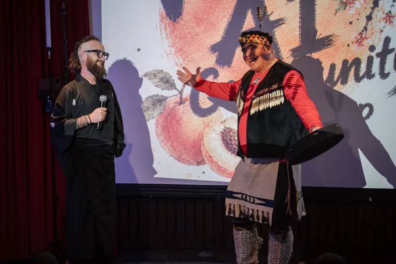 An Indigenous welcome unfolds on stage as the audience settles in — Wider angle.