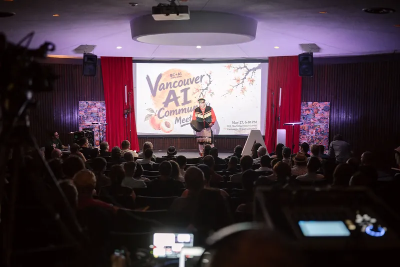 An Indigenous welcome unfolds on stage as the audience settles in — Closer on the mic.