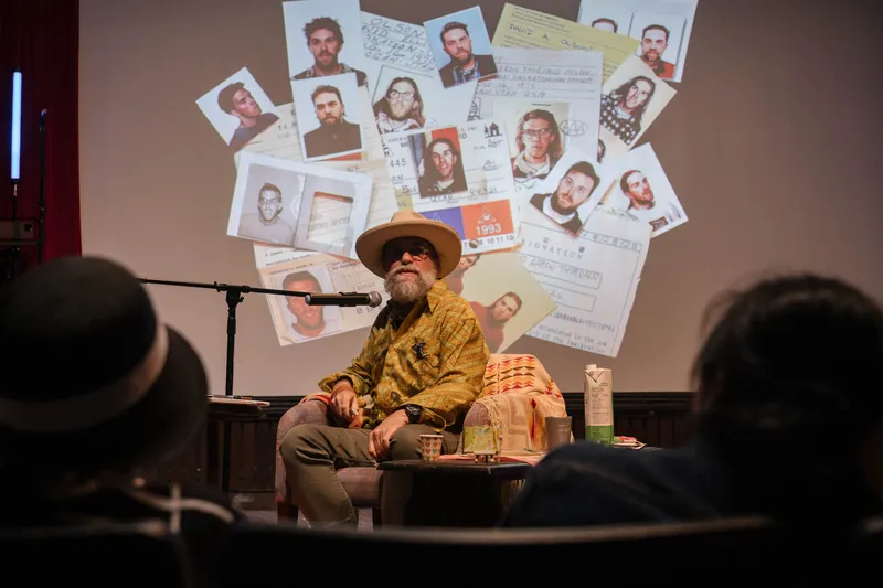 Dave Olson leans into storytelling — clippings, collages, and handwritten notes on screen — Closer on the mic.