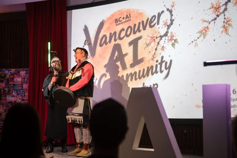 Welcome speakers share the stage — drum and mic catching the spotlight — From the aisle.