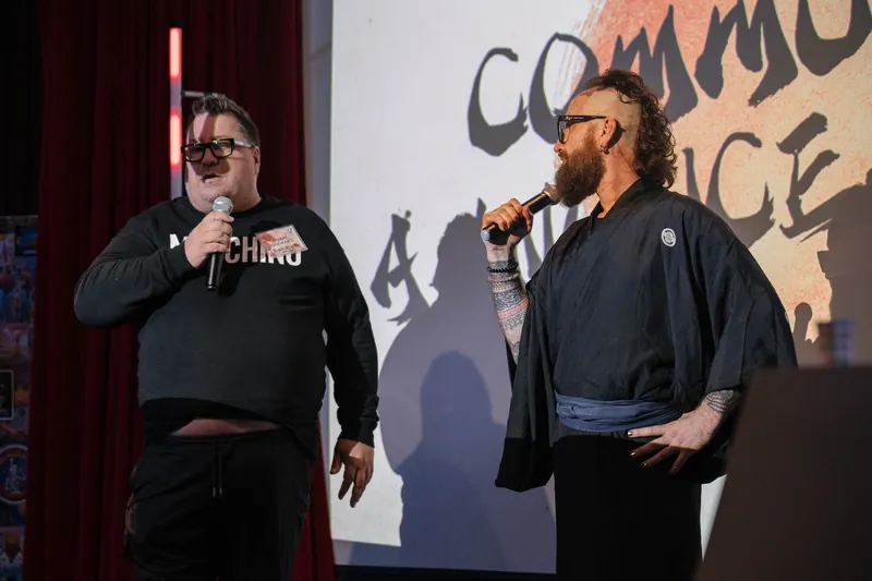 Community members take the mic for announcements under the peach slide — Stage-left view.