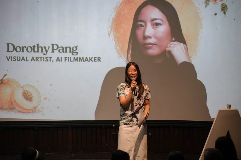 Dorothy Pang presents from the mic under her peach-illustrated intro slide — Soft focus on the crowd edge.