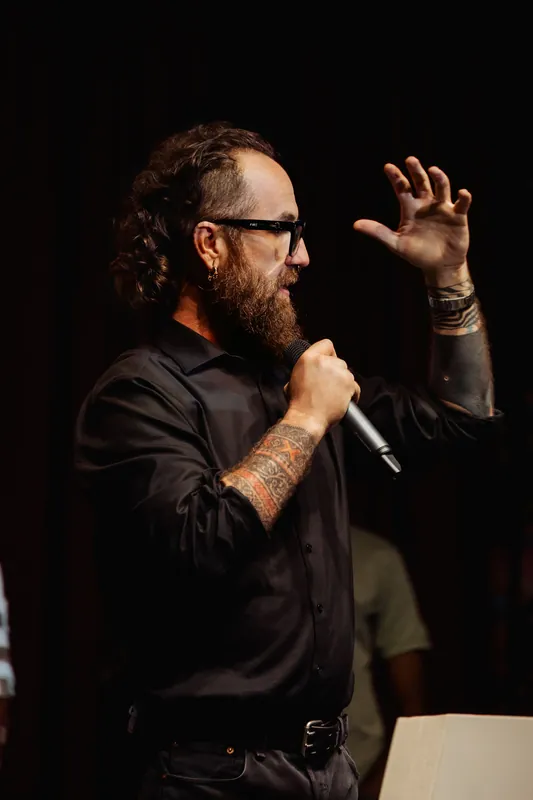 The host illustrates a point with a raised hand and microphone.