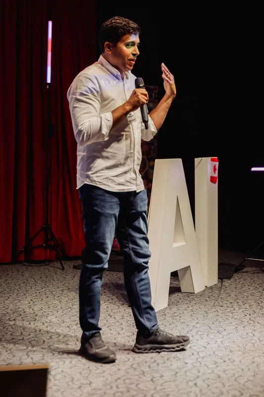 Taleeb Noormohamed raises a hand near his face while speaking.