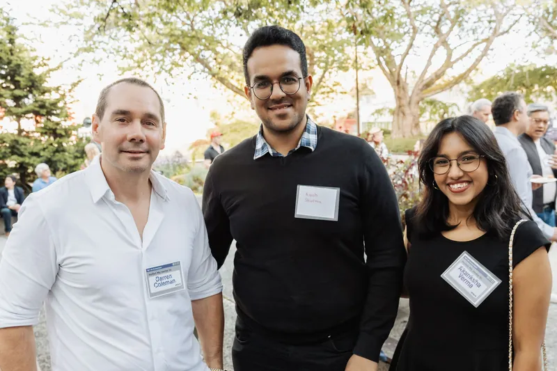 Four attendees smile together for a group portrait outdoors.