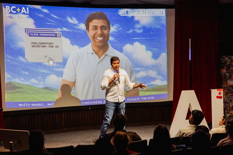 Taleeb Noormohamed speaks beneath a slide identifying him as Parliamentary Secretary for AI.