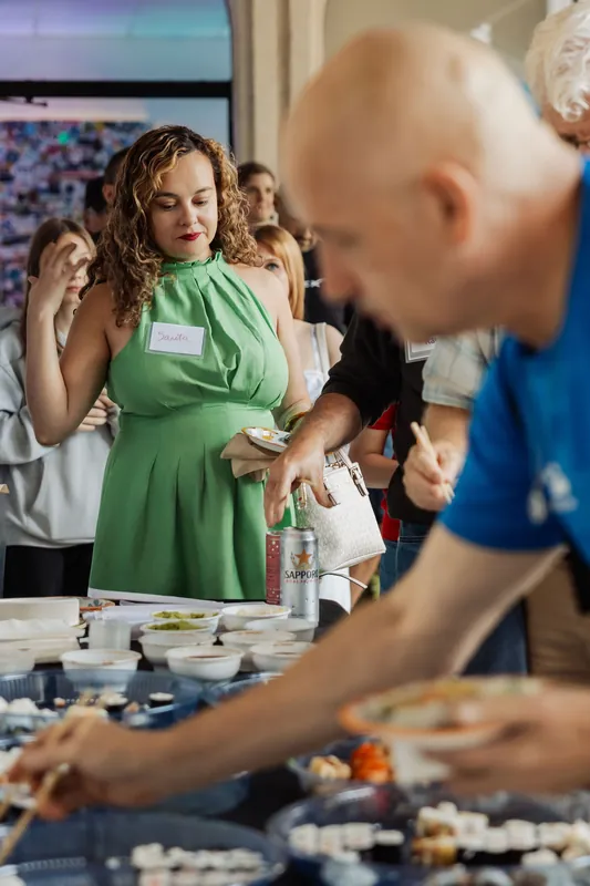 An attendee in green selects food from the reception buffet.