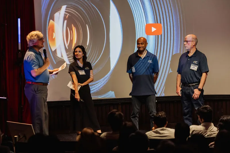 Four Data for Good representatives stand beneath a projected video screen.