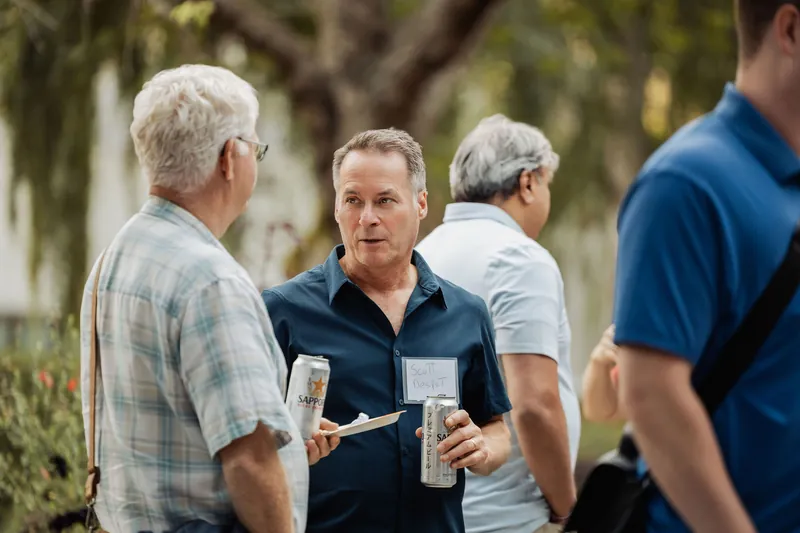 Two attendees talk amid the busy outdoor reception.