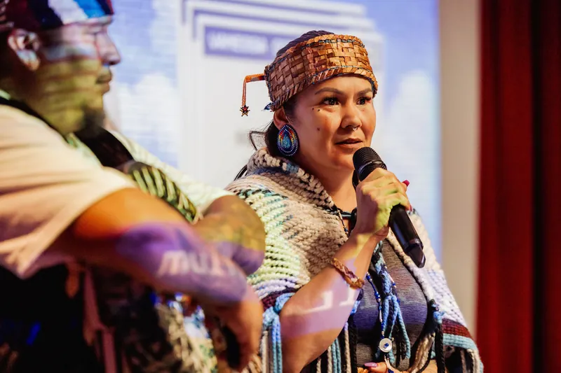 The welcome speaker looks toward the audience while holding a microphone.
