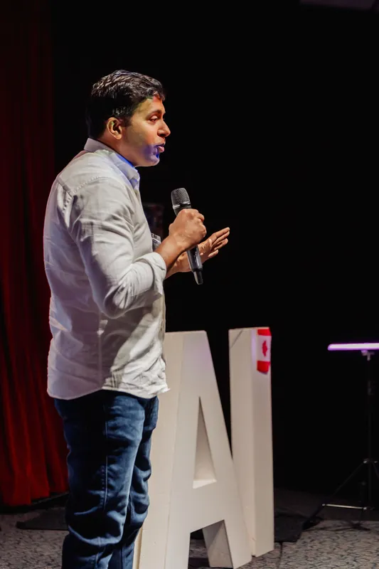 Taleeb Noormohamed gestures with one hand while addressing the audience.