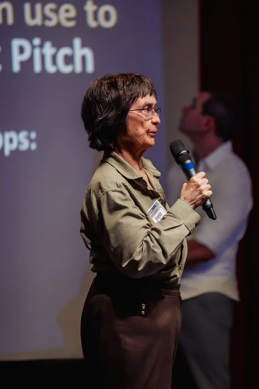 A presenter addresses the audience with a workshop slide behind her.