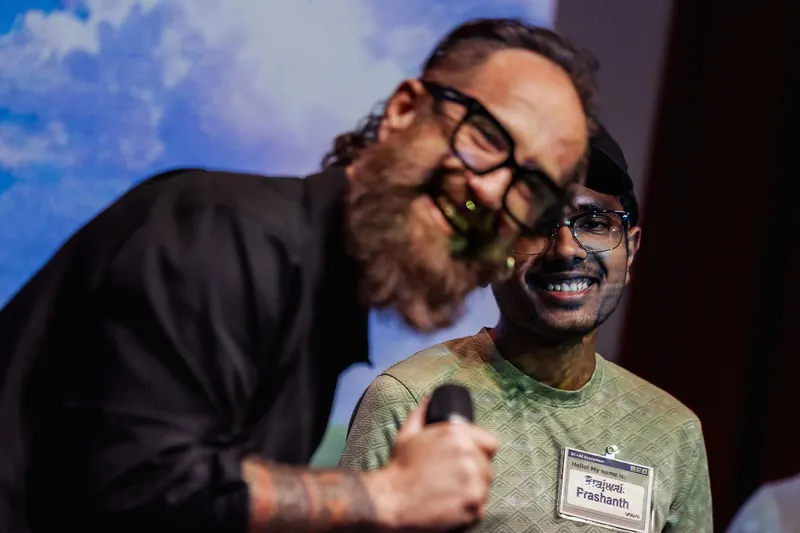 The host leans toward a smiling community participant during an introduction.